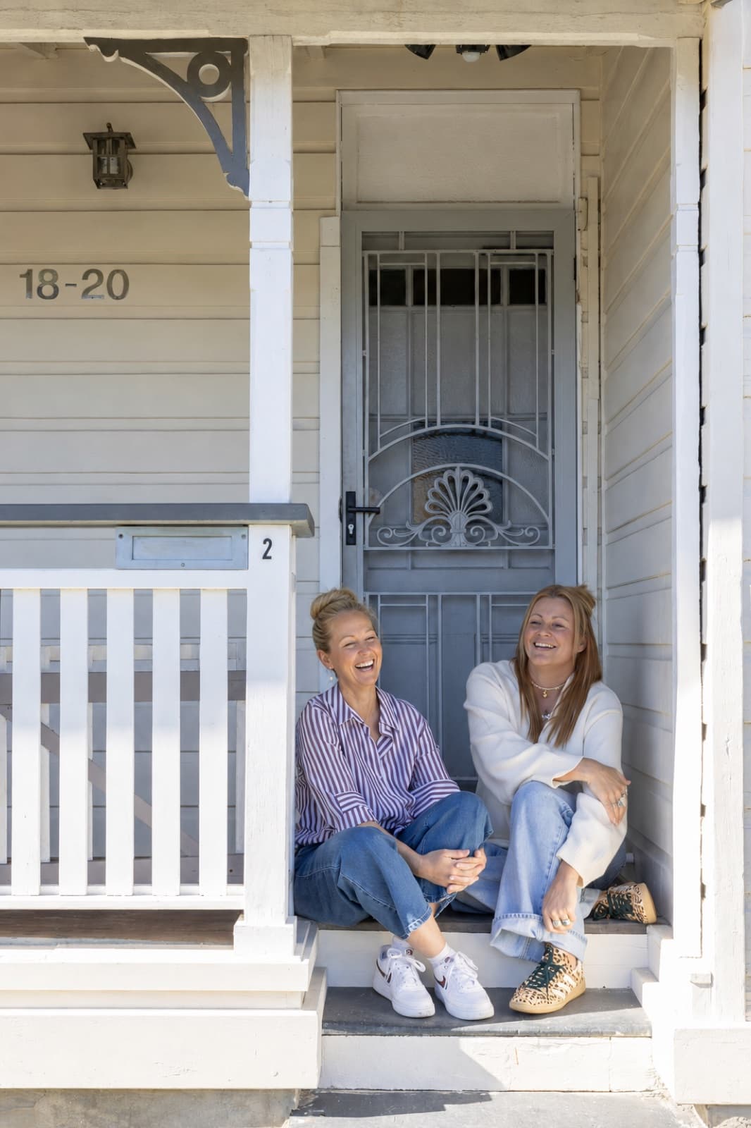 Small Folk founders Bec and Em laughing together on the verandah of the heritage cottage